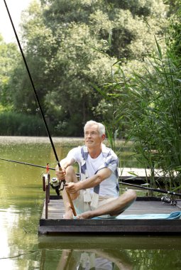 Senior man sitting at pier and fishing.