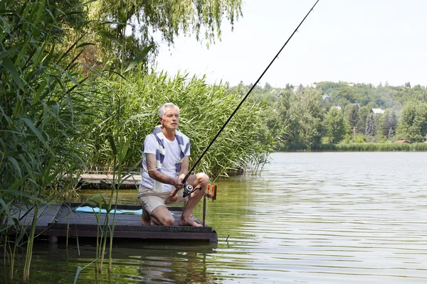 Senior man  at the lakeside and fishing. — Stock Photo, Image