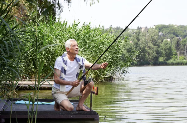 Senior man  at the lakeside and fishing.