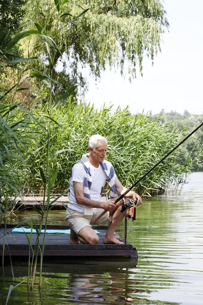 湖畔で釣りの年配の男性. — ストック写真