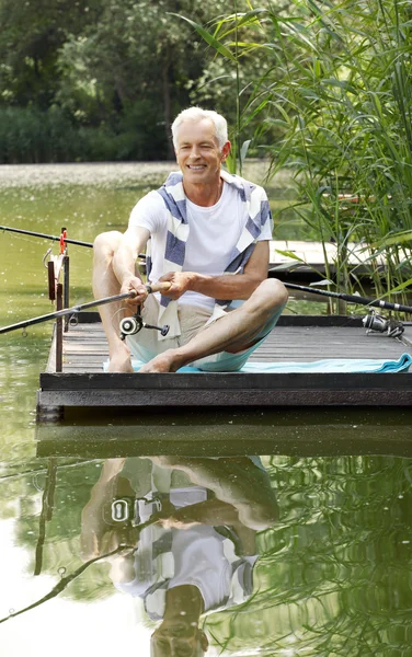 Senior man sitting at pier and fishing. — ストック写真