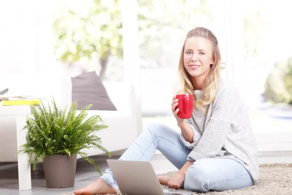 Woman using laptop while drinking tea — Stock Photo, Image