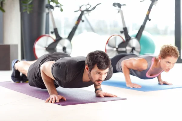 Žena a muž dělá push up v tělocvičně. — Stock fotografie