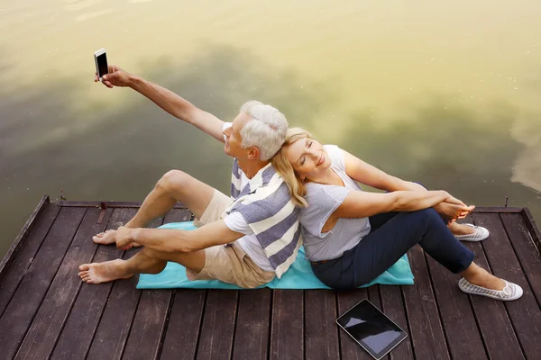 Senior people relaxing at lakeshore — Stock Photo, Image