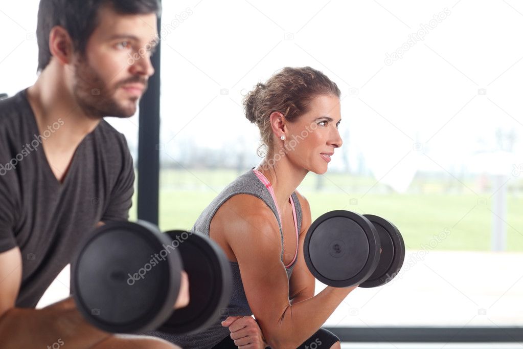 Woman and man lifting barbells