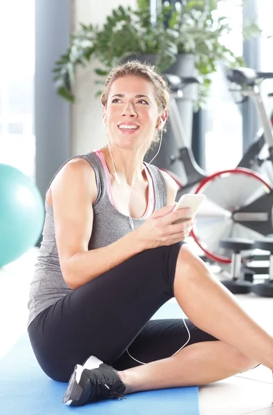 Kvinnan lyssnar musik efter fitnessutövaren — Stockfoto