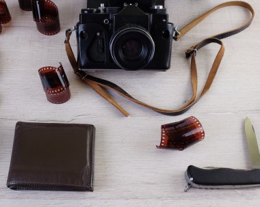 Fotoğrafçı, tasarımcı ya da hippi tarzı için alan iş. Bir film kamera, film, izle, m-cüzdan, bıçak üzerinde ahşap masa var.