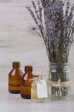 Taze çiçekler bir cam şişe bir arka plan üzerinde lavanta yağı