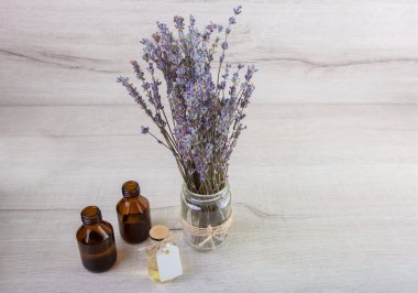 Taze çiçekler bir cam şişe bir arka plan üzerinde lavanta yağı