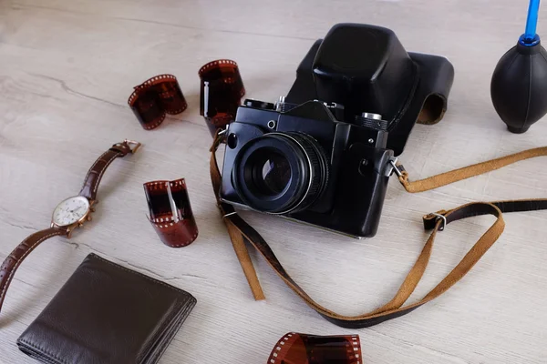 Work space for photographer, designer or hipster style. Have a film camera, film, watch, wallet, knife on wooden table.