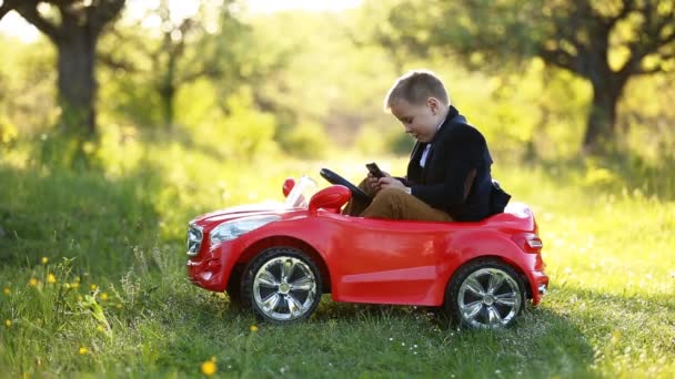 Menino monta um carro vermelho — Vídeo de Stock