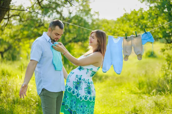 Mladí těhotná pár věšení prádla — Stock fotografie