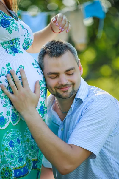 Šťastný otec poslouchá břicho těhotné manželky — Stock fotografie