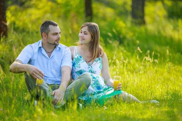 Feliz grávida casal beber suco de laranja — Fotografia de Stock