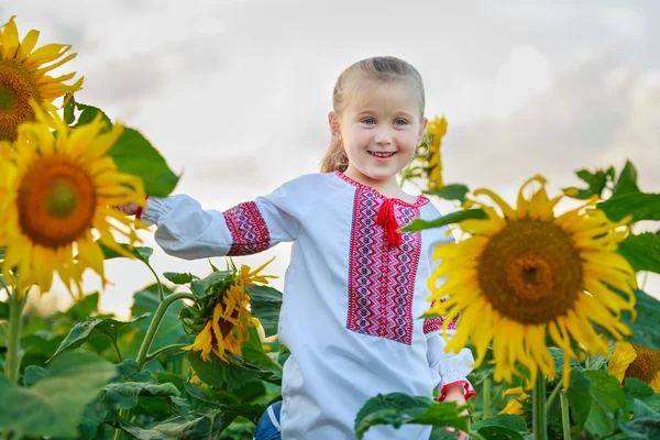 Kleines Mädchen auf dem Feld mit Sonnenblumen — Stockfoto