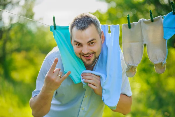 Homem perto da roupa das crianças pendurado em uma corda — Fotografia de Stock