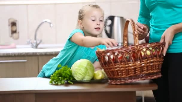 Dívka pomáhá její matka tahání zeleninu z koše — Stock video