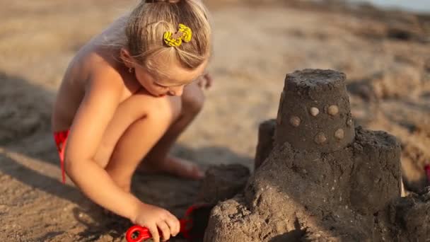 Menina constrói um castelo de areia — Vídeo de Stock