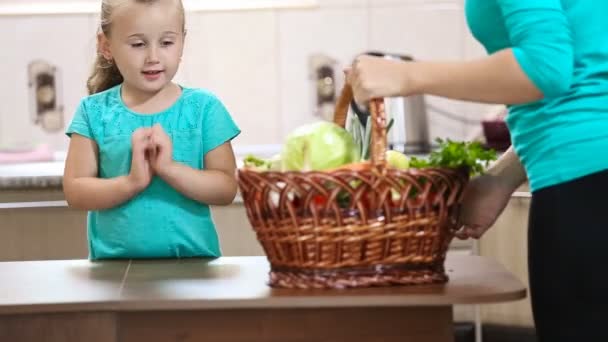 Menina ajuda sua mãe puxando legumes da cesta — Vídeo de Stock
