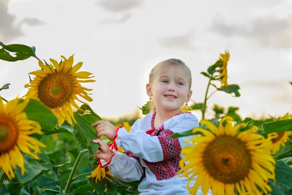 Kleines Mädchen auf dem Feld mit Sonnenblumen — Stockfoto