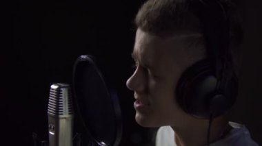 Stüdyo mikrofonunda şarkı söyleyen çocuk