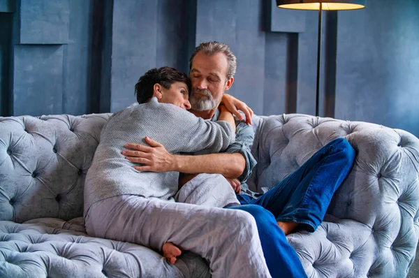 Couple hugging while sitting on the couch — Stock Photo, Image