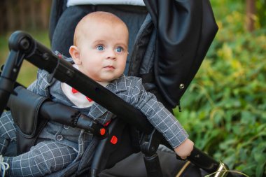 Küçük çocuk bebek arabasında oturuyor.