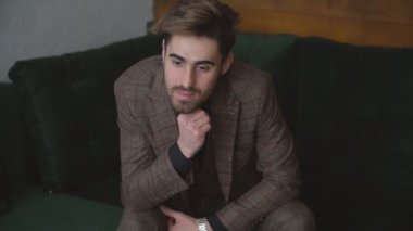 Takım elbiseli adam kanepede oturuyor.