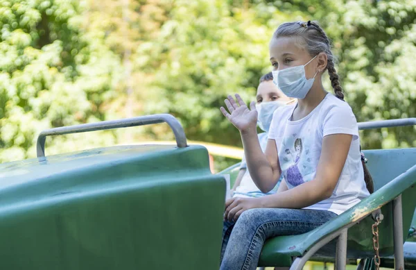 Children in medical masks ride the attraction — Stock Photo, Image