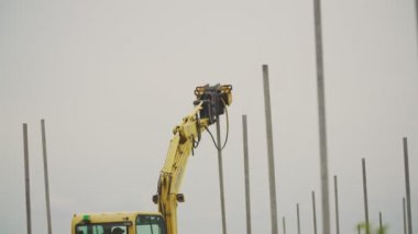 özel bir aygıta sahip bir kazıcı beton sütunları sürer