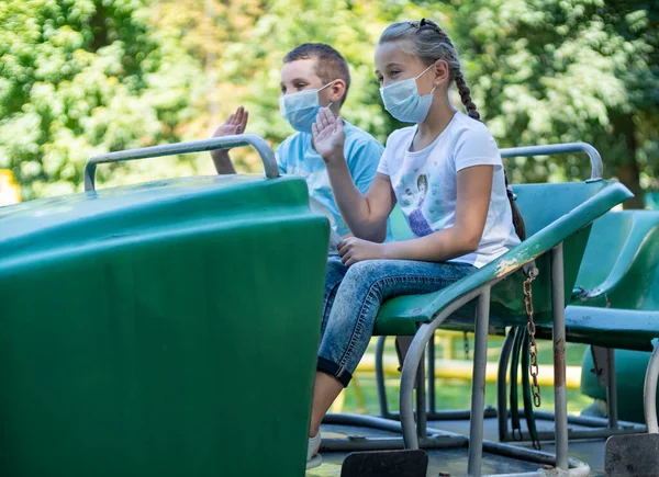 Children in medical masks ride the attraction — Stock Photo, Image