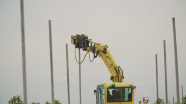 özel bir aygıta sahip bir kazıcı beton sütunları sürer