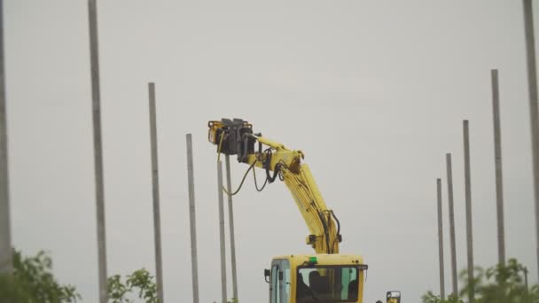 Özel bir aygıta sahip bir kazıcı beton sütunları sürer — Stok video