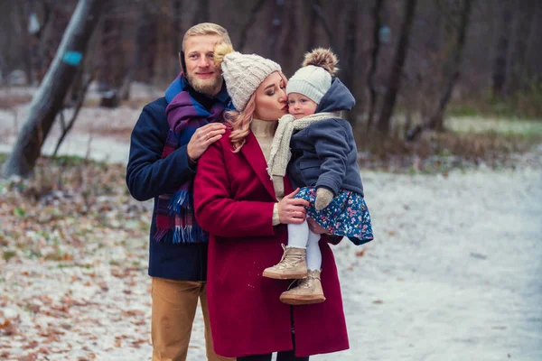 Молодая семья, гуляющая в парке зимой — стоковое фото
