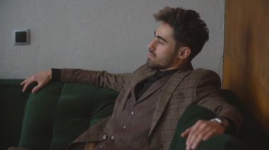 Takım elbiseli adam kanepede oturuyor.