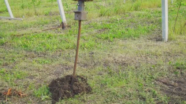 Schroeven van een metalen paal in de grond — Stockvideo