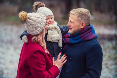 Genç bir aile kışın parkta yürüyor.
