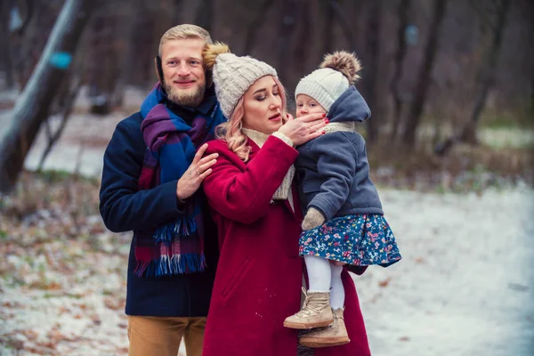 Молодая семья, гуляющая в парке зимой — стоковое фото