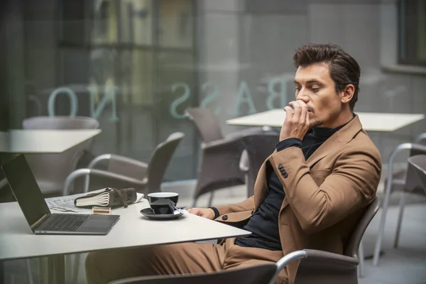 A man in a suit smokes at the table — Stock Photo, Image