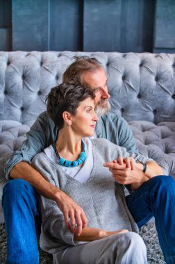 Kanepenin yanında oturan yaşlı çift.