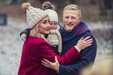 Kollarında çocuk olan bir ailenin portresi.