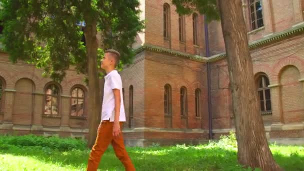Хлопчик ходить біля будівлі — стокове відео
