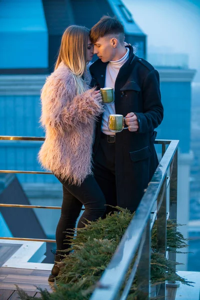 Pareja con tazas en la terraza de un edificio alto Fotos De Stock