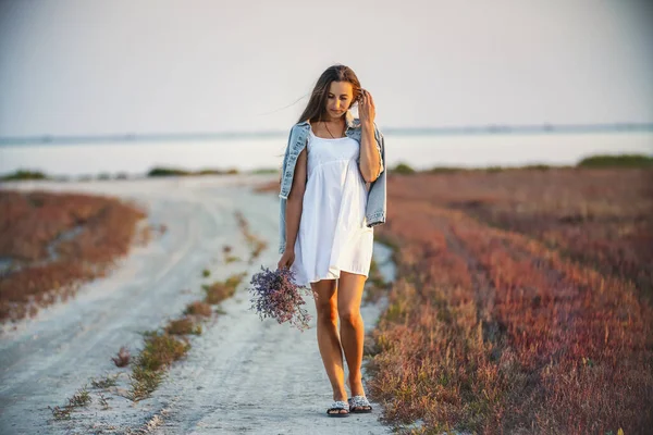 Mujer con un ramo de flores caminando por el camino — Foto de Stock