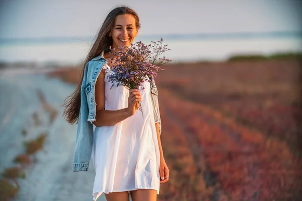 Femme avec un bouquet de fleurs marchant sur la route — Photo