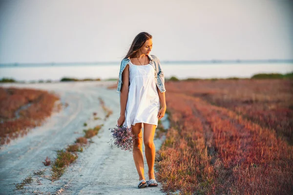 Mujer con un ramo de flores caminando por el camino — Foto de Stock