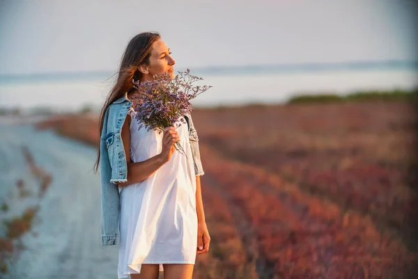 Femme avec un bouquet de fleurs marchant sur la route — Photo