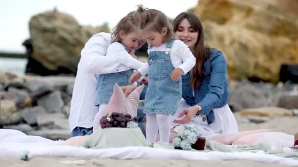 Család két gyerekkel ül a tengerparton — Stock videók