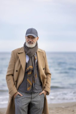 Yaşlı adam sahilde yürüyor.