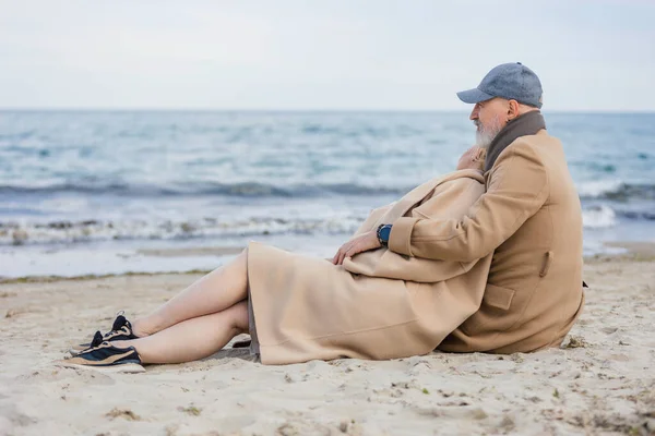 Betagtes Paar sitzt am Strand — Stockfoto